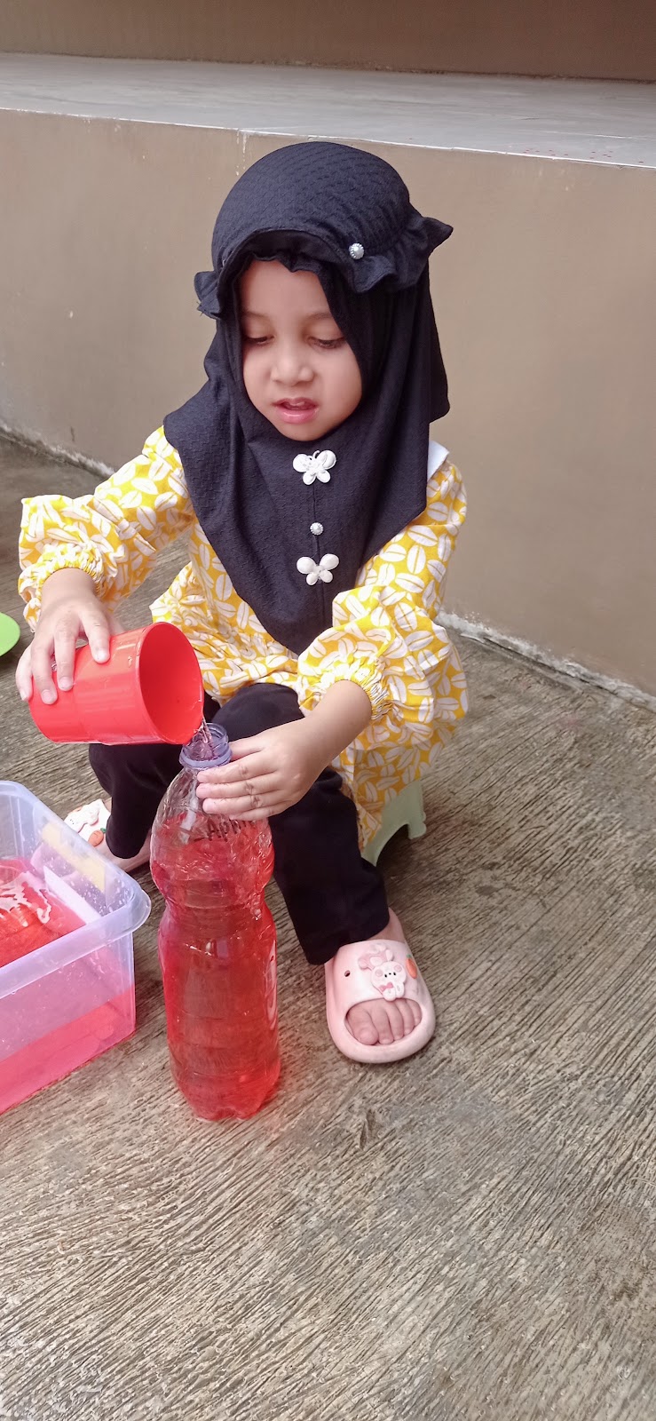 Anak berlatih menuang air sendiri di kegiatan bahan alam