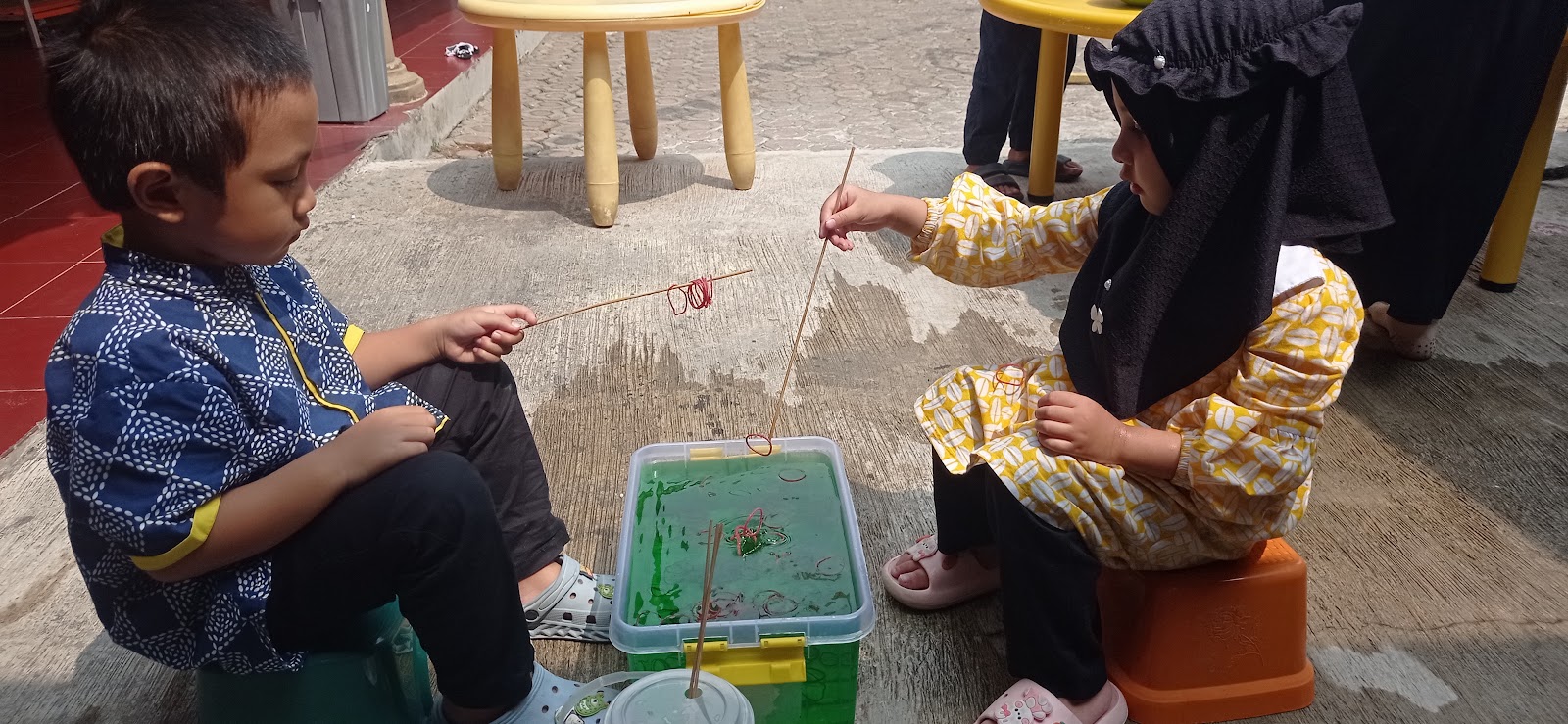 Anak memancing mainan di bak air saat bermain bahan alam