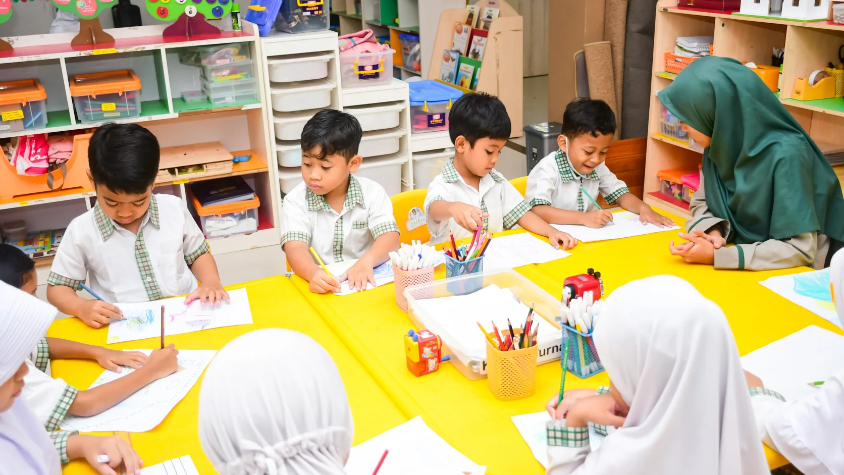 Anak-anak berkarya bersama guru di meja kelas